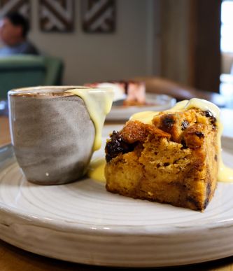 Slice of warm cake with caramel-like sauce drizzling from a mug on a plate.